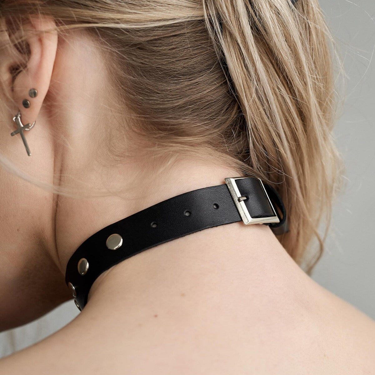 Black leather choker with silver buckle closure and metal studs