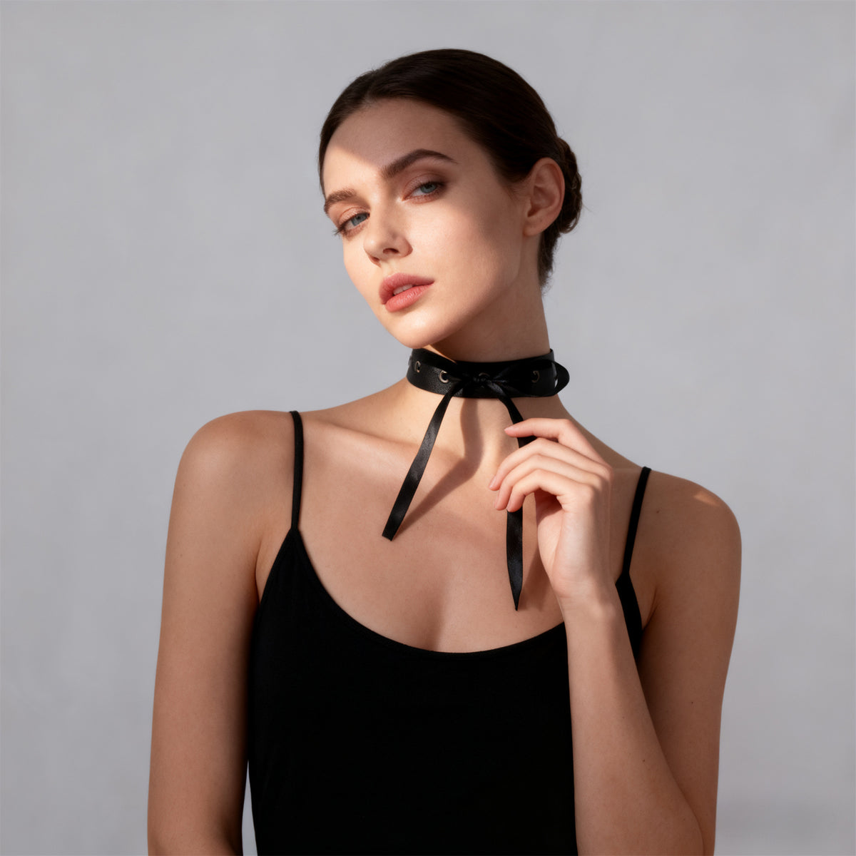 Black choker with knot-front ribbon and grommet eyelets around the neck