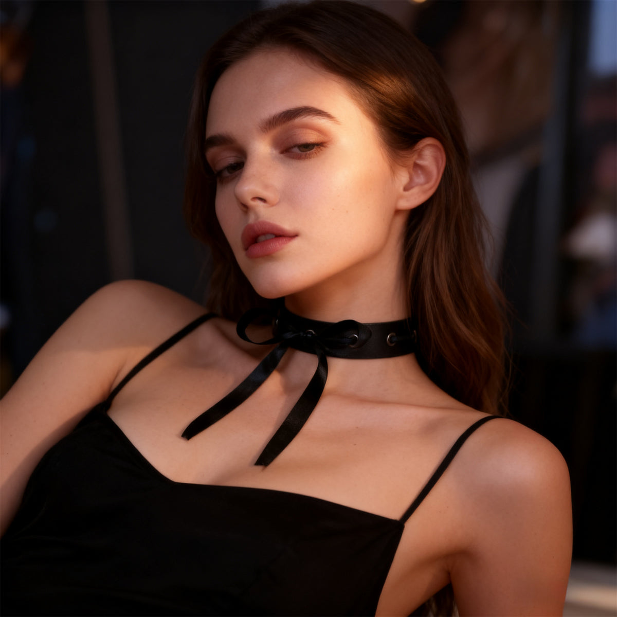 Black choker with grommet eyelets and ribbon straps draping across upper chest