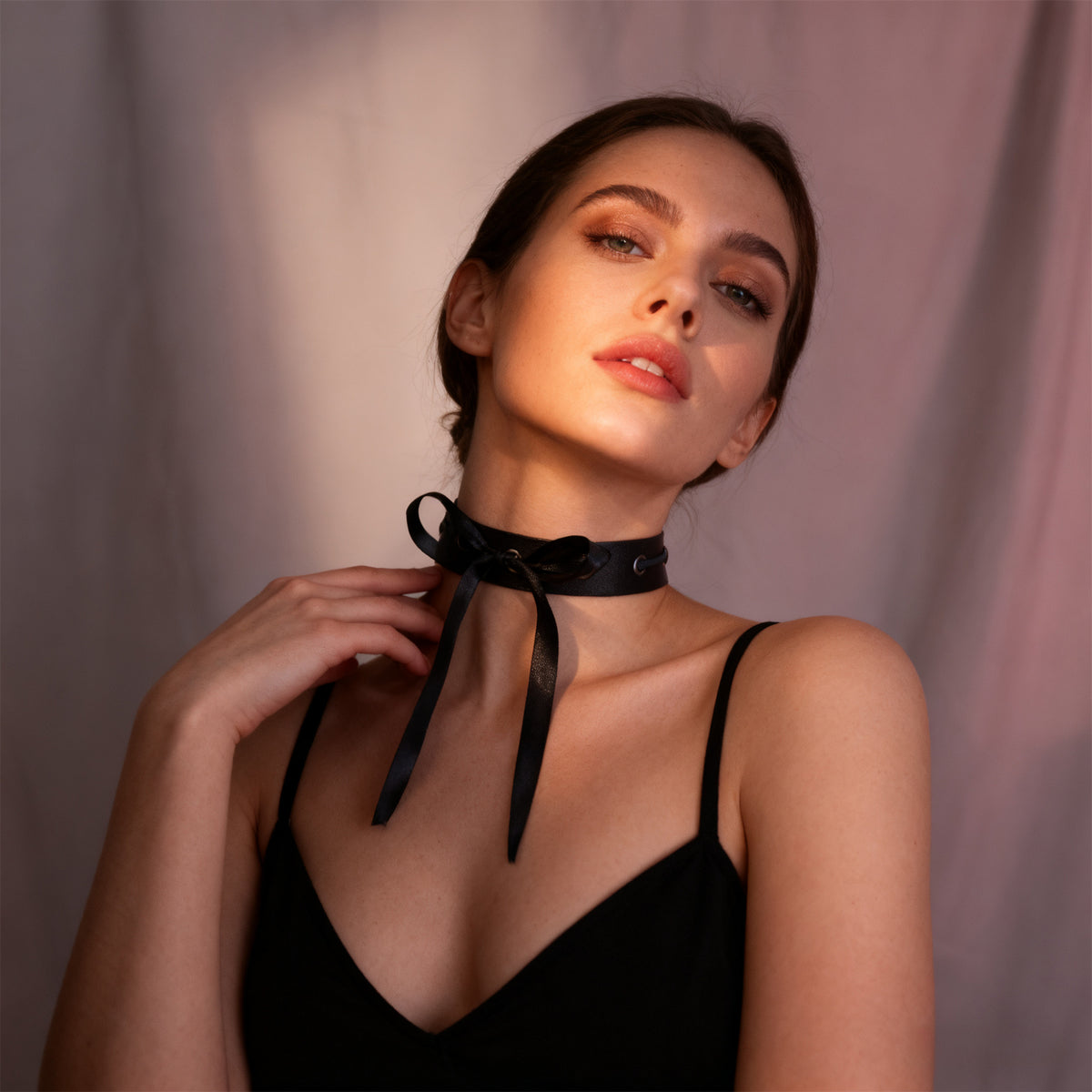 Black choker with long hanging ribbon ties and grommet eyelets at the neckline