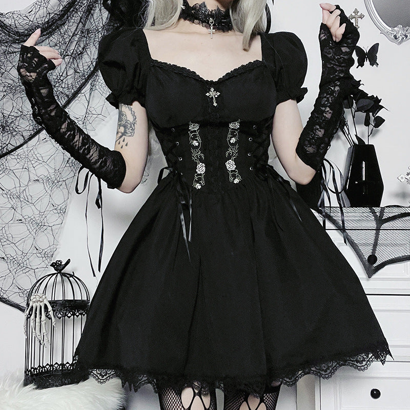 Person wearing a black gothic dress with lace details in a decorative setting.