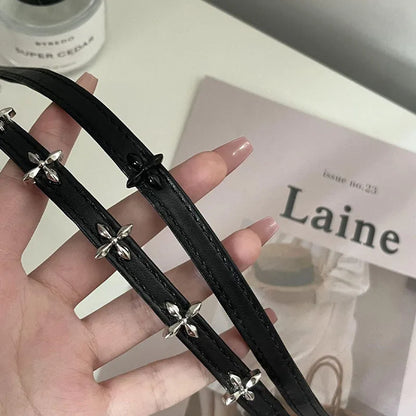 Black leather double-strap choker with silver cross charms, held in hand
