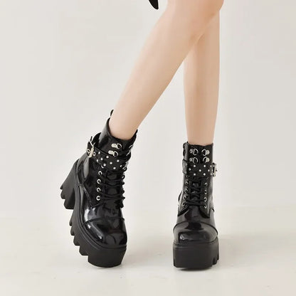 Black glossy lace-up boots with studded cuff straps and thick tread sole