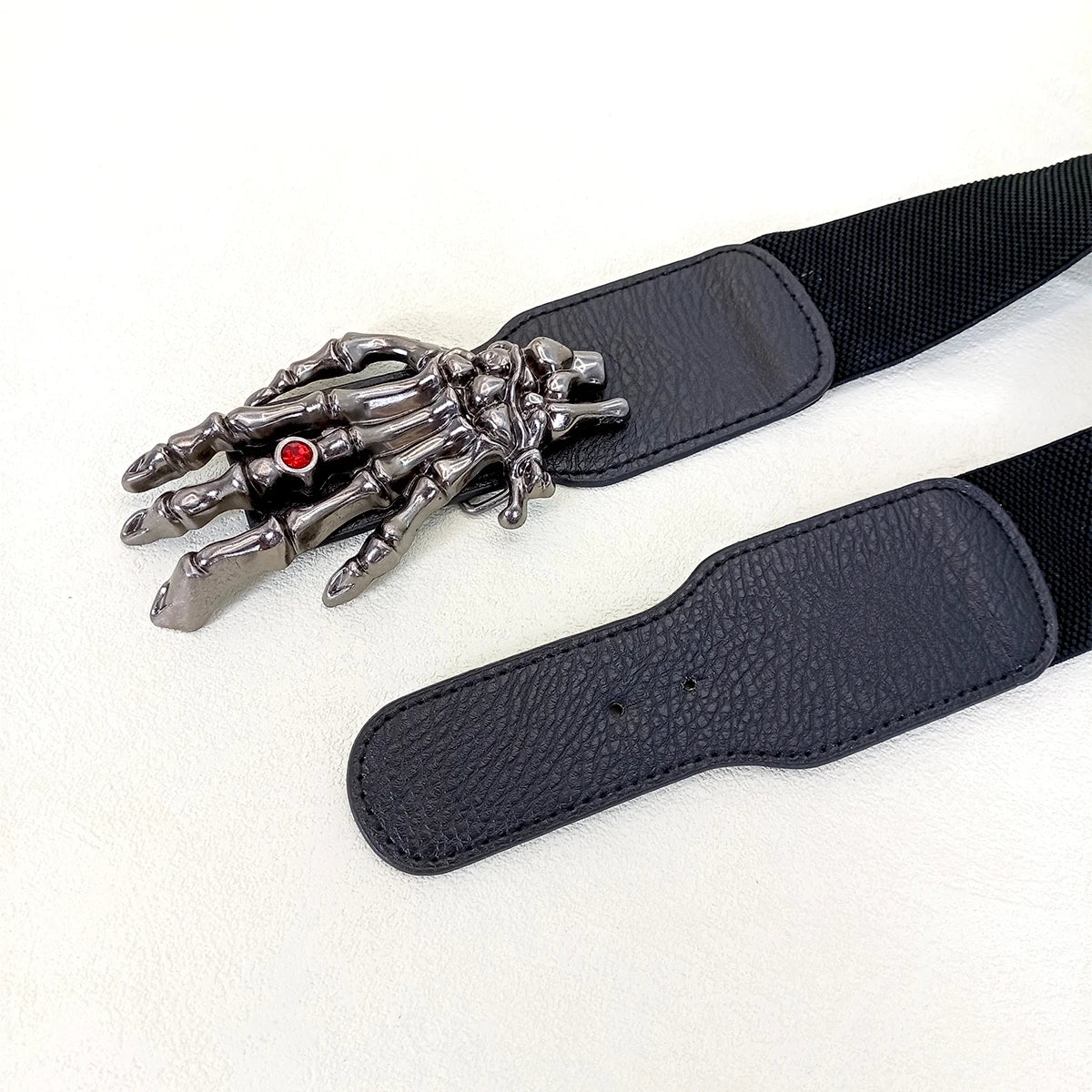Leather belt showing silver skeleton-hand buckle and textured strap, dark