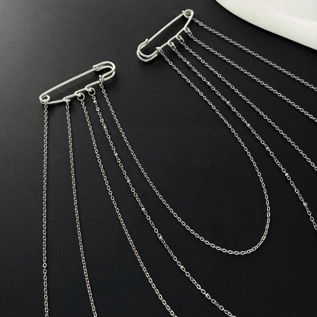 Set of layered silver chain drape necklaces with carabiner-style clasps, flat lay