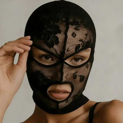 Black mesh face veil mask with floral lace pattern, hand adjusting near the temple