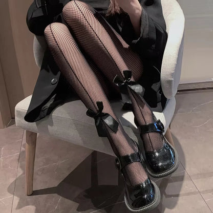 Dark lace fishnet stockings with black bow accents at the ankles