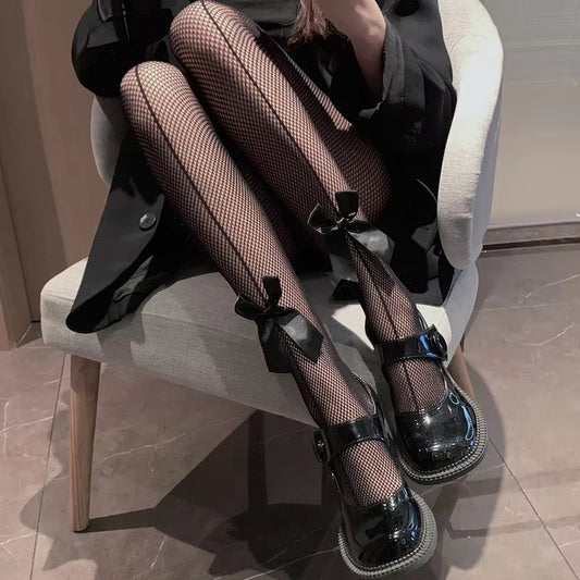 Dark lace fishnet stockings with black bow accents at the ankles