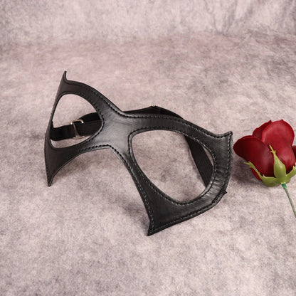 Black cat-eye mask with curved eye openings, visible stitching, elastic strap, flat lay