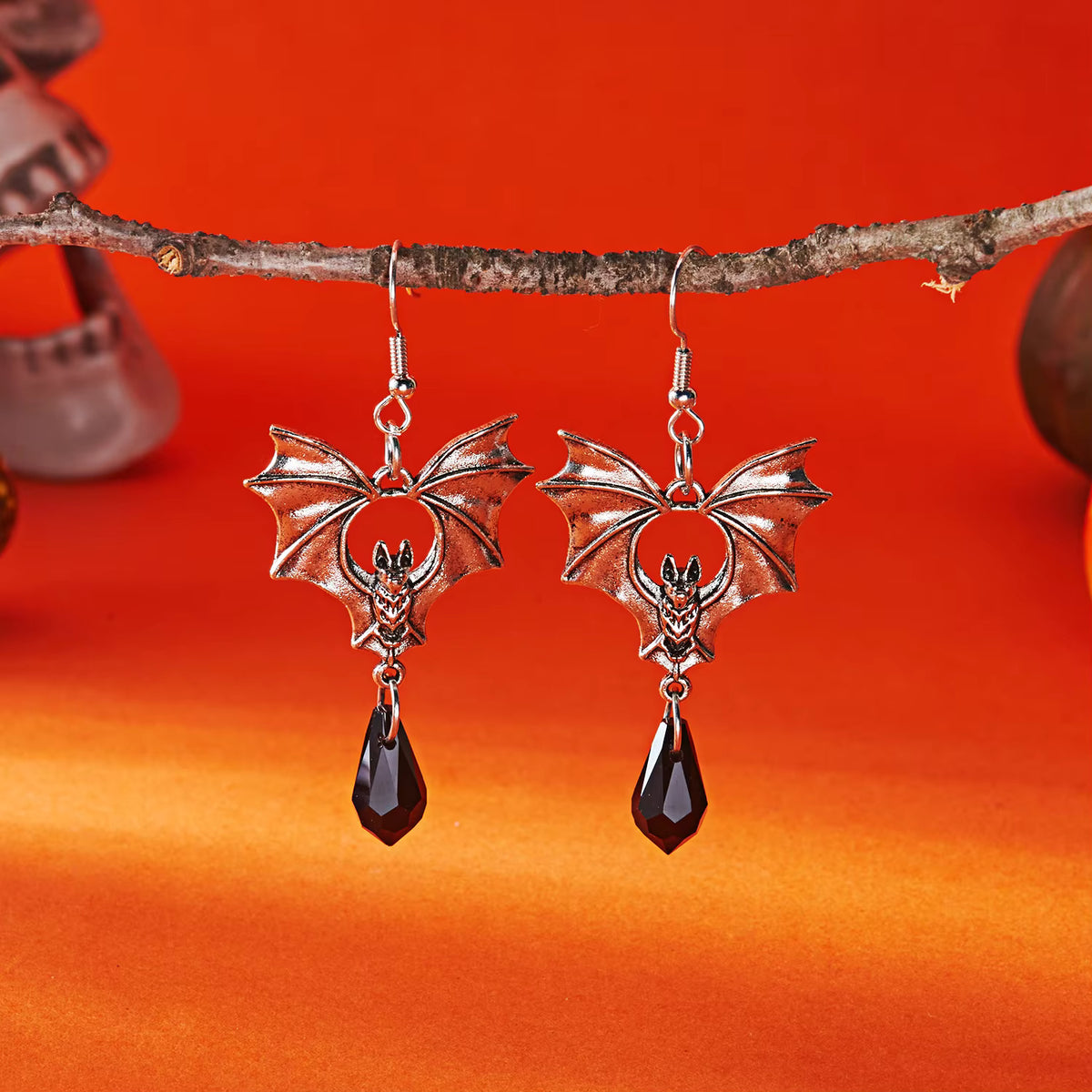Bat-shaped drop earrings with dark faceted teardrop charms, silver-tone hooks