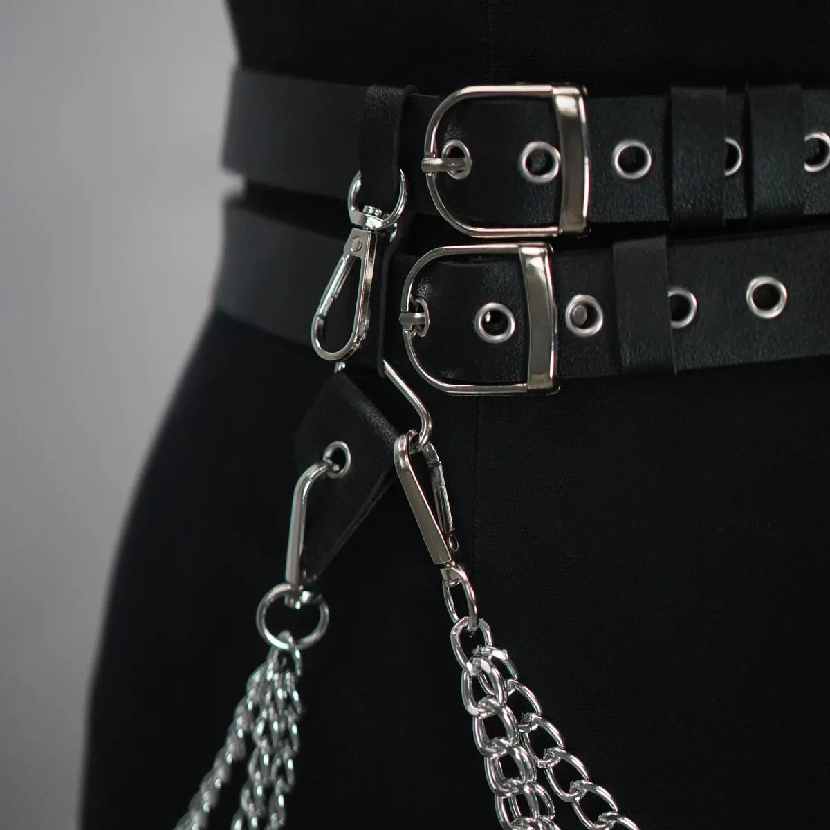 Black leather-look belt with silver buckles, rings, and dangling chain links