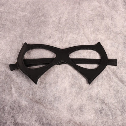 Black cat-eye mask with open eye cutouts, pointed cheek panels, elastic band, flat lay
