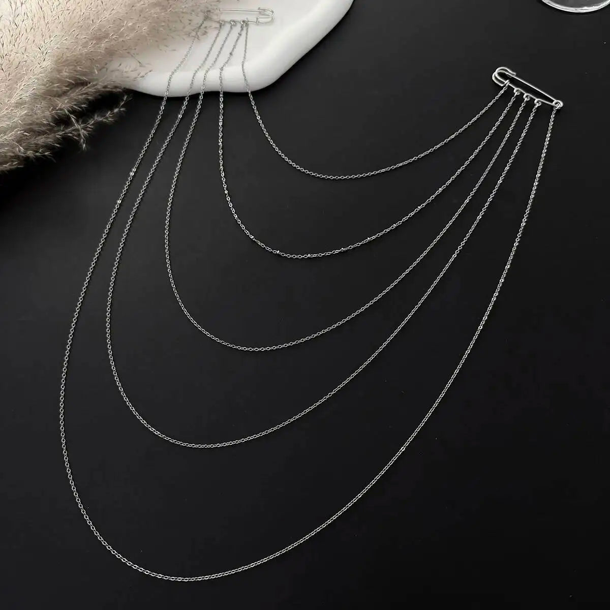 Layered silver chain drape accessory with five long curved chains, close-up