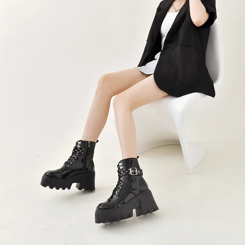 Black ankle boots with lace-up front, riveted strap buckles, and chunky sole
