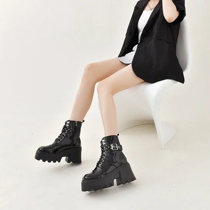 Black ankle boots with lace-up front, riveted strap buckles, and chunky sole