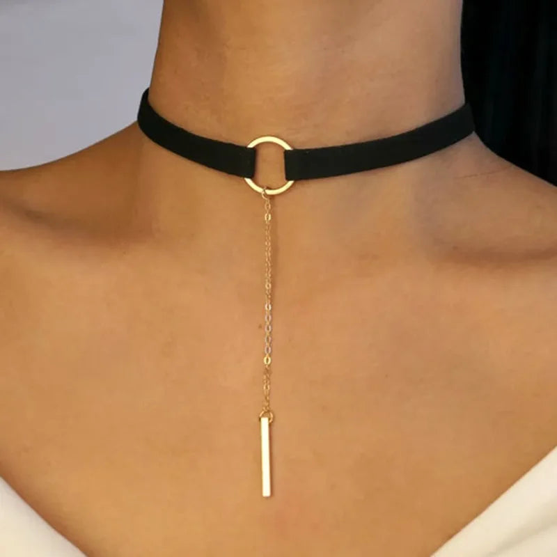 Black velvet choker with gold-tone ring and long bar pendant on a chain