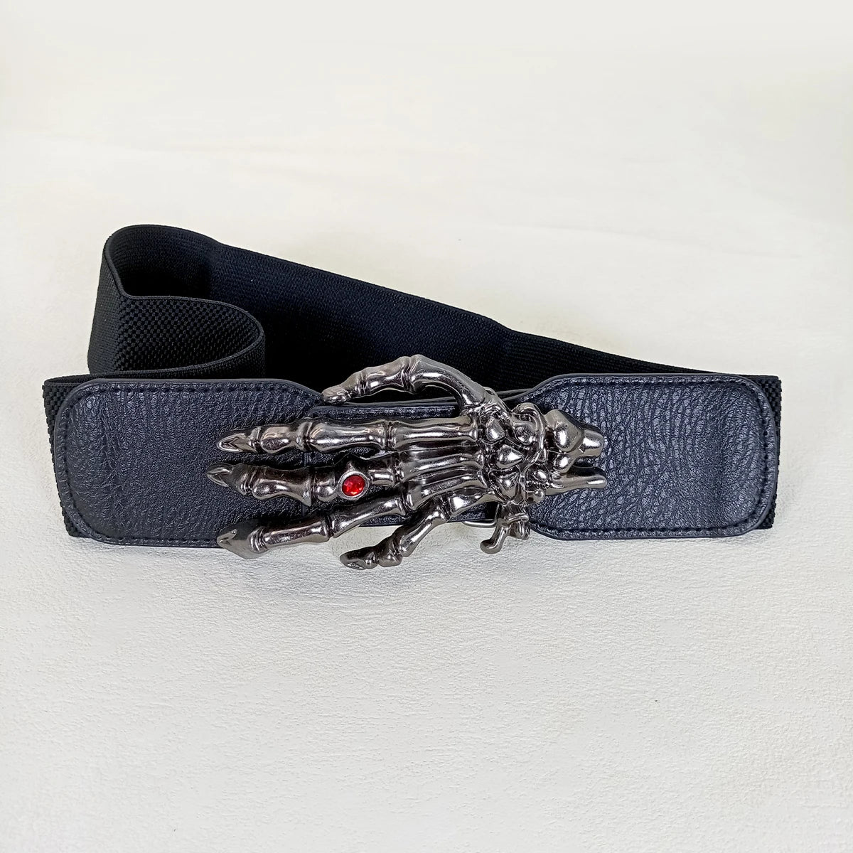 Wide dark leather belt with silver skeleton-hand emblem and red gem
