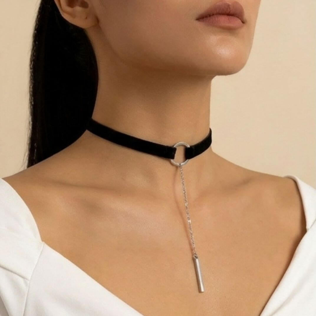 Black velvet choker with gold-tone ring and vertical bar pendant, worn on neck