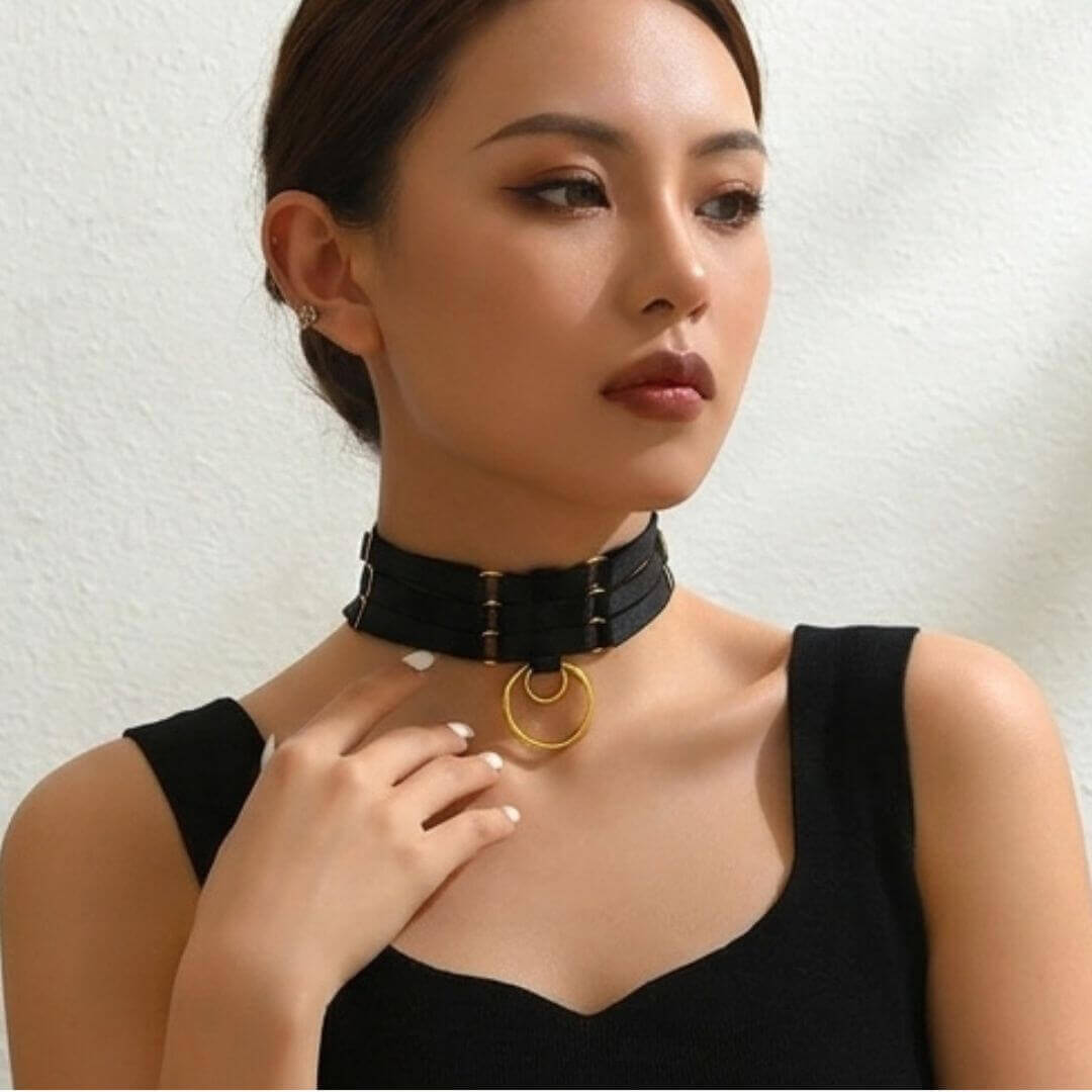 Black triple-ring choker worn by model, gold circular ring center on triple straps